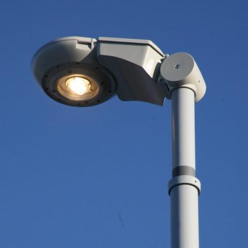 Nowoczesna latarnia uliczna pozwalająca na zmianę nachylenia oprawy. Oprawa 27 Synchro LED, w odcieniach szarości na tle błekitnego nieba